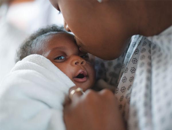 Closeup of a mother kissing her newborn