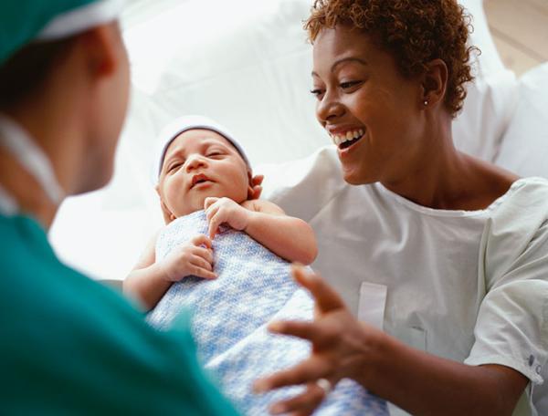 A clinician presents a new mother with her newborn