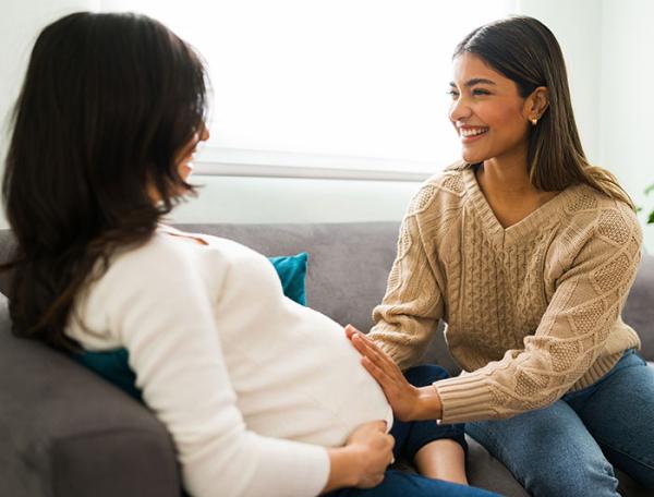 stock image of a pregnant woman and a doula seated on a sofa during a visit