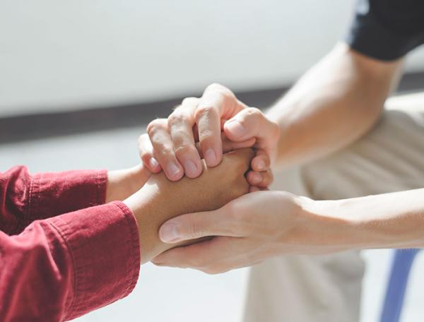 Adult hands clasping youth hands