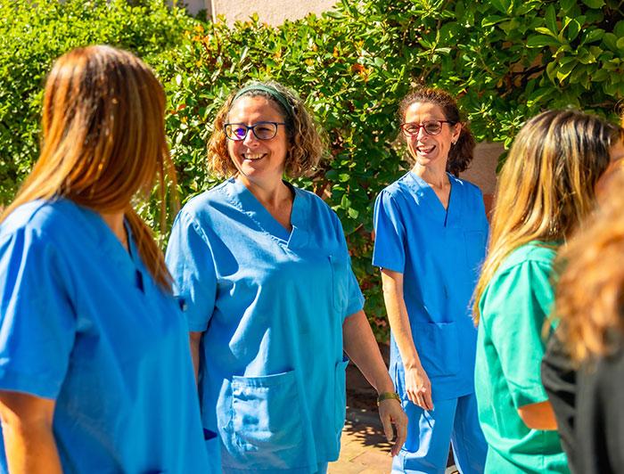 A team of health workers in scrubs walk outside