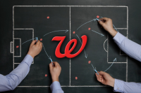 4 Insights into Walgreens’ Health Strategy Review. A soccer field chalkboard with the Walgreens logo in the center. Four hands with blue chalk are drawing up a strategy on the board.